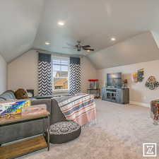 Carpeted bedroom featuring ceiling fan and vaulted ceiling