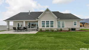 Rear view of house with central AC, a patio area, and a yard