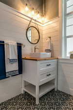 Bathroom featuring tile patterned floors, wooden walls, and vanity