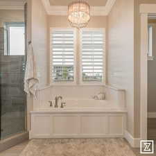 Bathroom featuring shower with separate bathtub, ornamental molding, and a notable chandelier