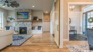 Living room featuring a fireplace, light hardwood / wood-style flooring, and ceiling fan with notable chandelier