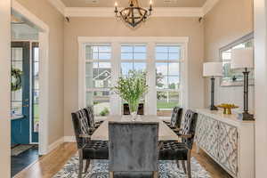 Dining space featuring a notable chandelier, dark hardwood / wood-style flooring, and ornamental molding