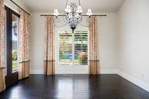 Unfurnished living room featuring hardwood / wood-style flooring and a chandelier