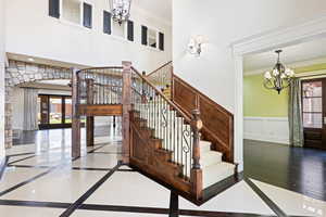 Stairs with a notable chandelier, crown molding, and hardwood / wood-style floors