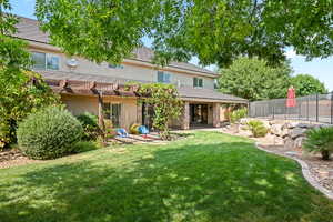 Rear view of property with a pergola, a patio, and a lawn