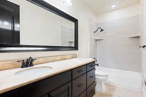 Full bathroom featuring vanity, tiled shower / bath, and toilet