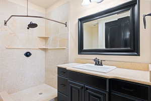 Bathroom featuring vanity and a tile shower