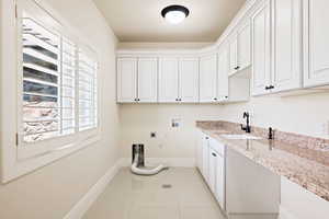 Laundry room with light tile patterned flooring, cabinets, washer hookup, electric dryer hookup, and sink