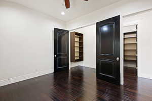 Unfurnished bedroom featuring ceiling fan, dark hardwood / wood-style flooring, a closet, and a walk in closet