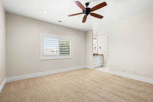 Interior space with light carpet and ceiling fan with jack and jill bathroom.