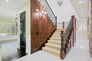 Stairway featuring tile patterned flooring, crown molding, and a chandelier