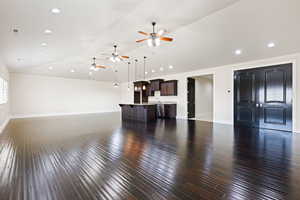 Unfurnished living room with hardwood / wood-style floors, ceiling fan, and vaulted ceiling