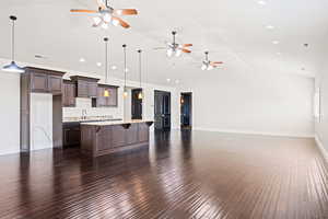 Kitchen with a center island, ceiling fan, hanging light fixtures, wood-type flooring, and dark brown cabinetry