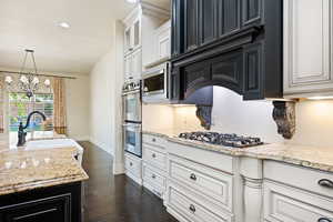 Kitchen featuring sink, dark hardwood / wood-style flooring, stainless steel appliances, and light stone counters