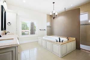 Master Bathroom with tile patterned flooring, a bath, and an inviting chandelier