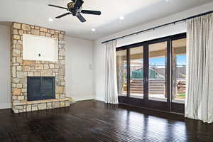 Unfurnished living room with a stone fireplace, ceiling fan, and hardwood / wood-style flooring