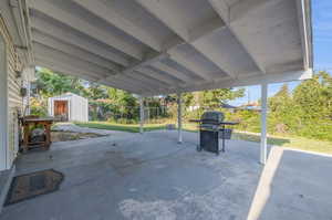 View of patio featuring area for grilling and a storage shed