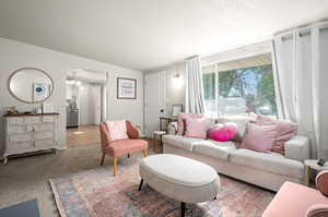 Living room featuring a textured ceiling, carpet floors, and an inviting chandelier