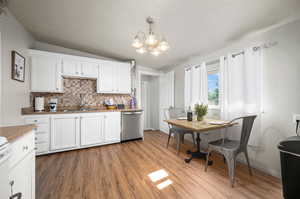 Kitchen featuring a notable chandelier, decorative light fixtures, hardwood / wood-style floors, dishwasher, and vaulted ceiling