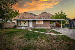 View of front of property featuring a lawn, a mountain view, and a carport