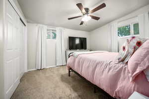 Carpeted bedroom featuring ceiling fan and a closet