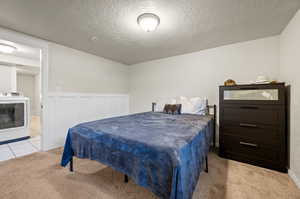 Carpeted bedroom featuring washer / clothes dryer and a textured ceiling