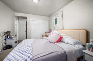 Carpeted bedroom with a closet and a textured ceiling