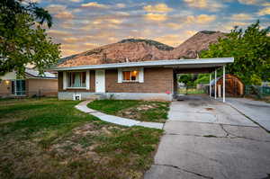 Single story home featuring a mountain view and a lawn