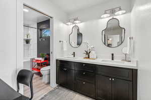 Bathroom with wood-type flooring, toilet, and dual bowl vanity