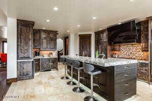 Kitchen with dark brown cabinetry, a kitchen island, a breakfast bar area, and tasteful backsplash