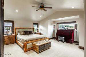 Carpeted bedroom featuring ceiling fan and lofted ceiling