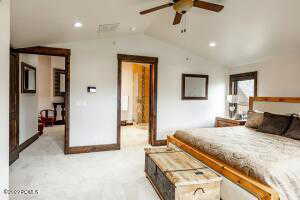 Carpeted bedroom featuring ceiling fan and vaulted ceiling