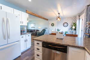 Kitchen featuring white fridge, dishwasher, white cabinets, and dark wood-type flooring