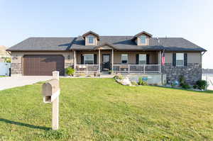 View of front of home with covered porch, a garage, and a front lawn