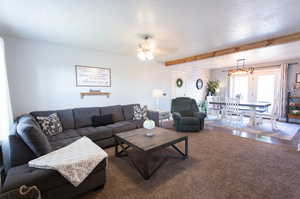 Living room featuring a textured ceiling, ceiling fan, wood-type flooring, and beam ceiling