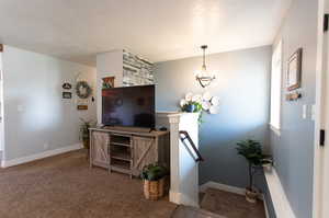 Interior space featuring an inviting chandelier, carpet floors, and a textured ceiling