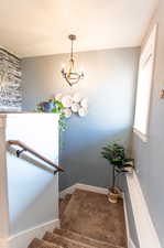 Staircase featuring a chandelier and carpet flooring