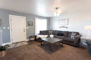 Carpeted living room featuring ceiling fan