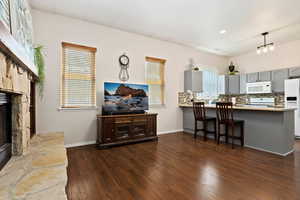 Interior space featuring white appliances, gray cabinetry, kitchen peninsula, a healthy amount of sunlight, and dark hardwood / wood-style floors