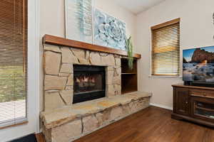 Living room with a stone fireplace and dark hardwood / wood-style floors