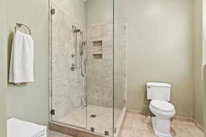 Bathroom with an enclosed shower, tile patterned flooring, and toilet