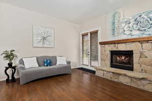 Living room with a fireplace and dark wood-type flooring