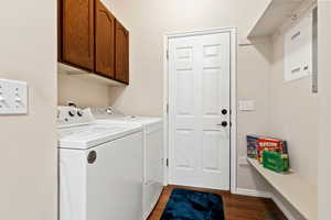 Laundry area with independent washer and dryer, wood-type flooring, and cabinets