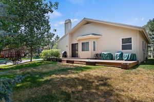 Rear view of property with a deck and a lawn