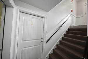 View of stairway and exterior door to unit with laundry room on the left