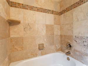 Bathroom with combined tub and shower with travertine tile surround