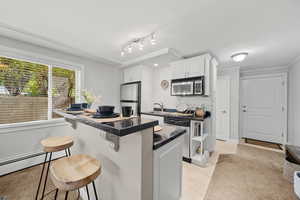 Kitchen featuring stainless steel appliances, a breakfast bar, white cabinetry, and granite countertops