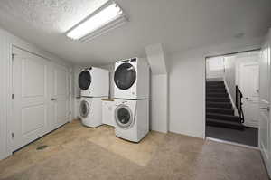 Large shared laundry room with tile, new carpet, new full-size dryers, stacked washers, and storage cabinets just outside of unit