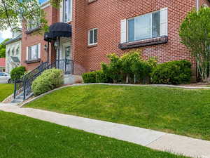 Lovely entrance with awning, lawn, and rose bushes