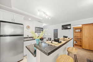 Open kitchen with stainless steel appliances, a center island, white cabinetry, and granite countertops